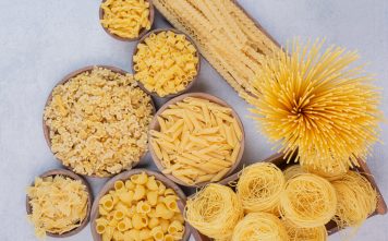 Tasty raw pasta and macaroni on wooden bowls