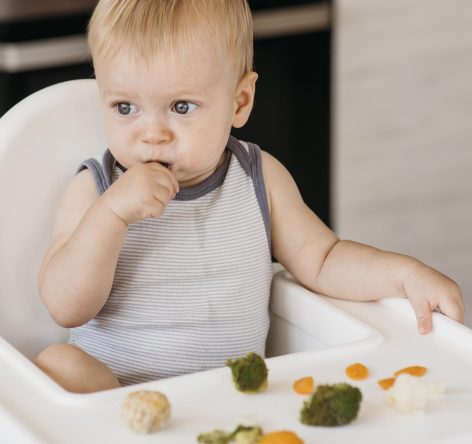 cute-baby-boy-in-highchair-eating-vegetables